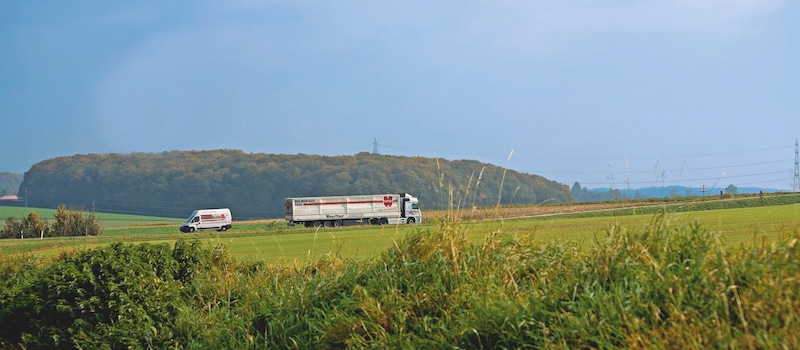 LKW und Kleintransporter auf Landstraße zwischen Feldern